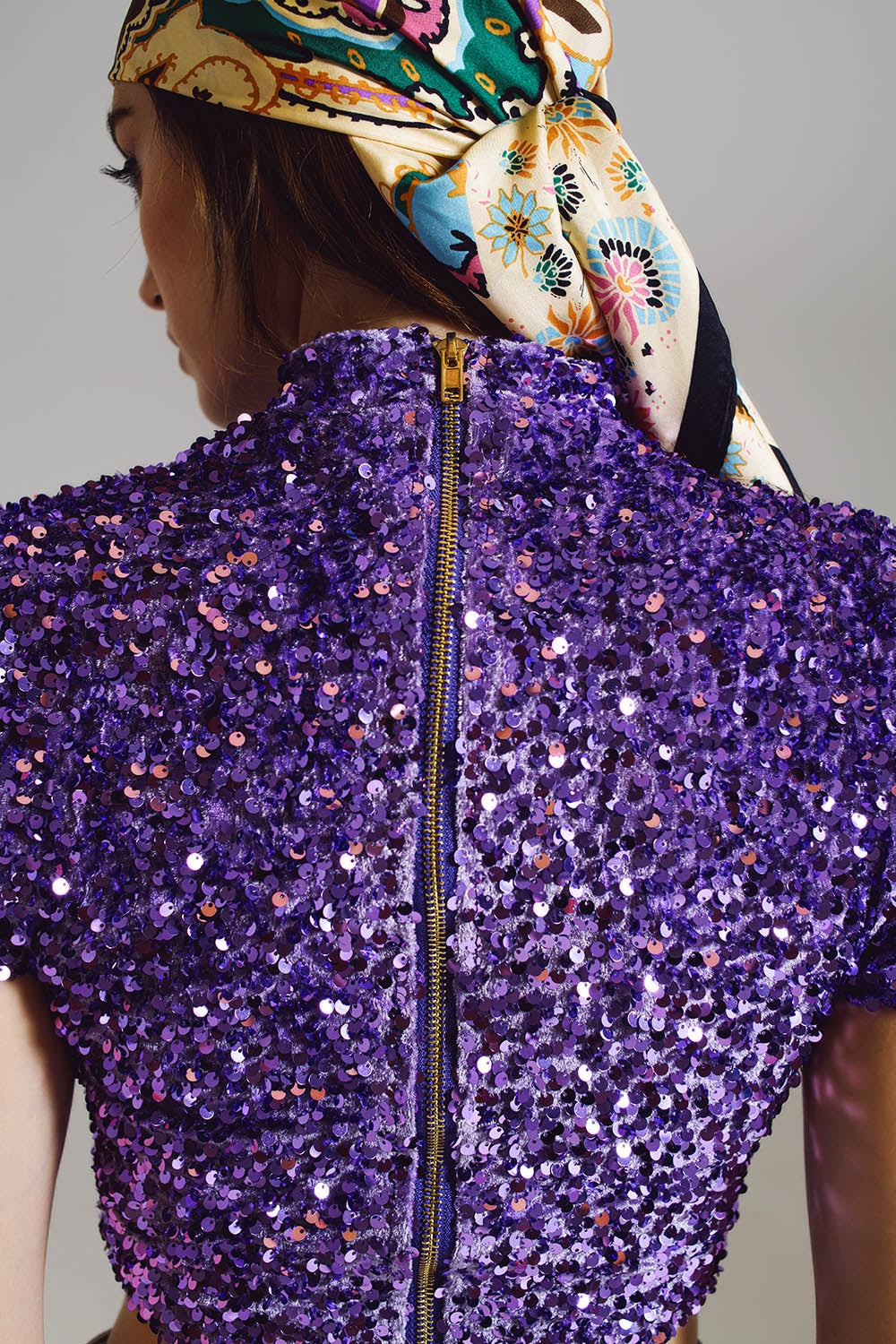 Back view of sparkly metallic purple zip up shirt on women. 